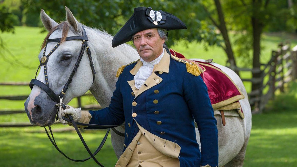 man in period clothing holding white horse with fence and trees in background at Presidents' Weekend George Washington at Colonial Williamsburg in Williamsburg, Virginia, USA